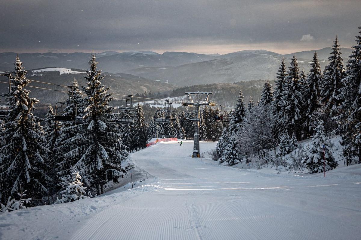 Snow-covered spruce slopes and a chairlift line at a Carpathian ski resort in the late afternoon